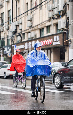 Radfahrer gekleidet in regenbekleidung in einer regnerischen Wetter. Shanghai hat einen feuchten subtropischen Klimas, der Sommer ist sehr warm und schwül. Stockfoto