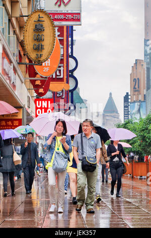 Shopper mit Regenschirm in den nassen Nanjing East Road. Shanghai hat einen feuchten subtropischen Klimas, der Sommer ist sehr warm und schwül. Stockfoto