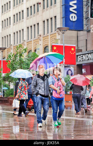 Trichter mit Regenschirm in den nassen Nanjing East Road. Shanghai hat einen feuchten subtropischen Klimas, der Sommer ist sehr warm und schwül. Stockfoto