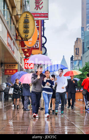 Shopper mit Regenschirm in den nassen Nanjing East Road. Shanghai hat einen feuchten subtropischen Klimas, der Sommer ist sehr warm und schwül. Stockfoto