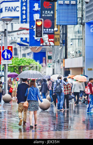 Shopper mit Regenschirm in den nassen Nanjing East Road. Shanghai hat einen feuchten subtropischen Klimas, der Sommer ist sehr warm und schwül. Stockfoto