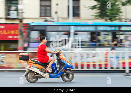 XIANG YANG-CHINA-1. JULI 2012. Frau auf dem e-Bike am 1. Juli 2012 in Xiang Yang. E-Bikes sind auf den Straßen in China schwärmen. Nationwid Stockfoto