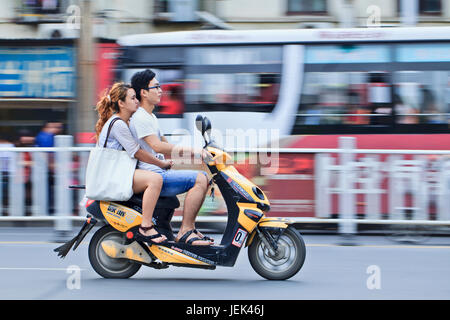 XIANG YANG - CHINA - 1. Juli. Chinesische junges Paar auf einem Elektrofahrrad. E-Bikes sind wimmelte es auf der Straße in China. Stockfoto