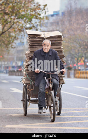 YIWU - CHINA - JAN. 8, 2016. Ältere Menschen Transporte Pappe auf ein Dreirad. Ältere Bevölkerung von China (60 oder älter) ist derzeit rund 128 Millionen Euro. Stockfoto