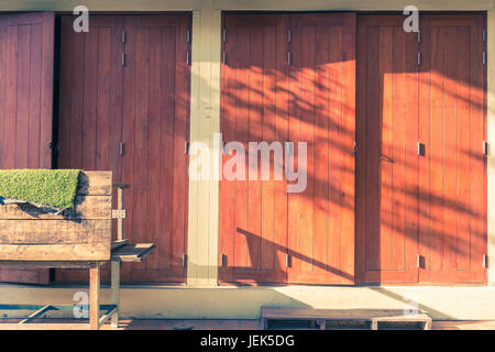 warmen Abendlicht mit Blatt Schatten scheint auf alten Stil Holztüren in Vintage Farbton, gut für Vintage Themen-Hintergrund Stockfoto