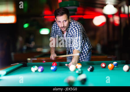 Jungen Mann spielen Pool in bar allein mit dem Ziel Stockfoto