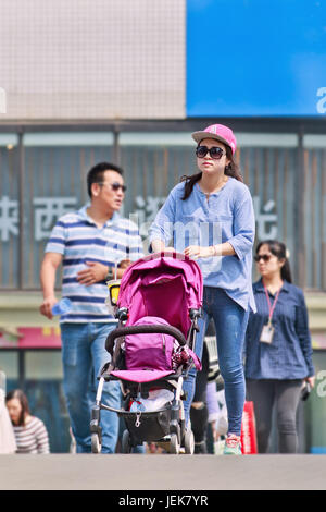 PEKING, 28. APRIL 2016. Junge Mutter mit Baby Auto auf Fußgängerbrücke. China hat die ein-Kind-Politik verworfen und es Paaren erlaubt, zwei Kinder zu haben. Stockfoto