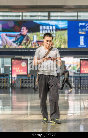 PEKING-21. MAI 2016. Modischer junger Mann am Bahnhof Peking Süd, dem größten Bahnhof der Stadt und einem der größten in Asien. Stockfoto