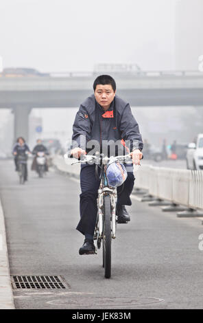 PEKING-OCT. 11,2014. Radfahrer in Smog bedeckten Stadt. Eine Konzentration von PM2.5, kleinen Partikeln, die ein enormes Risiko für die menschliche Gesundheit darstellen. Stockfoto