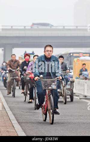 PEKING-OCT. 11,2014. Radfahrer in Smog bedeckt Stadt. Eine Konzentration von PM2.5, kleinen Partikeln, die ein enormes Risiko für die menschliche Gesundheit darstellen. Stockfoto