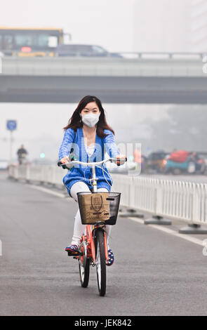 PEKING-OCT. 11,2014. Mädchen auf einem Fahrrad in Smog bedeckt Stadt. Eine Konzentration von PM2.5, kleinen Partikeln, die ein großes Gesundheitsrisiko darstellen. Stockfoto