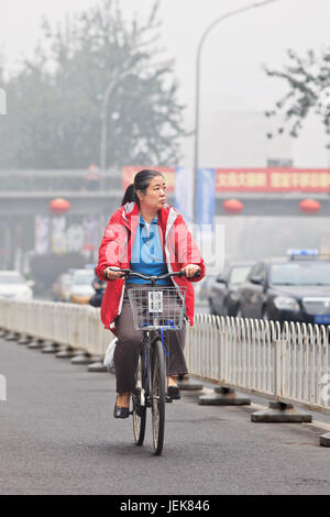 PEKING-OCT. 11,2014. Ältere Zyklen in Smog bedeckten Stadt. Eine Konzentration von PM2.5, kleinen Partikeln, die ein großes Gesundheitsrisiko darstellen. Stockfoto