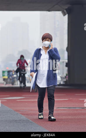 PEKING-OCT. 11,2014. Junge Frau mit Mundkappe in Smog blanketed Stadt. Die Verschmutzung in Peking war so dicht, dass sie mit dem nuklearen Winter vergleichbar war. Stockfoto