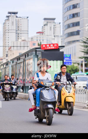 KUNMING - 30. JUNI 2014. Cooler Kerl auf einem E-Bike. Schätzungsweise 200 Millionen Chinesen verwenden jetzt E-Bikes, 1.000-mal mehr als vor 15 Jahren. Stockfoto