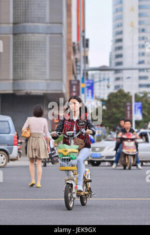 KUNMING - 30. JUNI 2014. Junges Mädchen auf dem E-Bike. In einem Jahrzehnt stieg Chinas E-Bike-Bevölkerung von fast Null auf 150 Millionen. Stockfoto