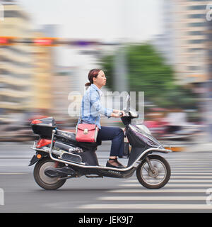 KUNMING - 5. JULI 2014. Junge Frau auf dem Elektrobike. Viele Elektrofahrräder in China sind das E-Bike im Roller-Stil, das Pedale haben kann oder nicht. Stockfoto