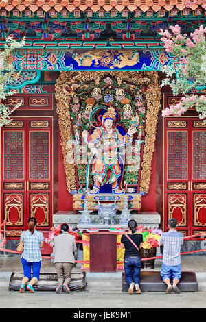 KUNMING - 8. JULI 2014. Anbeter vor dem kunstvollen Altar im Yuantong-Tempel. Der Yuantong-Tempel ist der bekannteste buddhistische Tempel in Kunming. Stockfoto