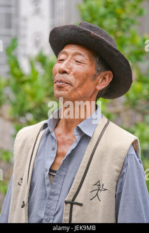 LIJIANG-CHINA-SEPT. 23, 2006. Ein Naxi-Senior singt in einem Garten. Naxi-Minderheit lebt in Lijiang, Sichuan und Tibet, ihre Einwohnerzahl beträgt 308.893. Stockfoto