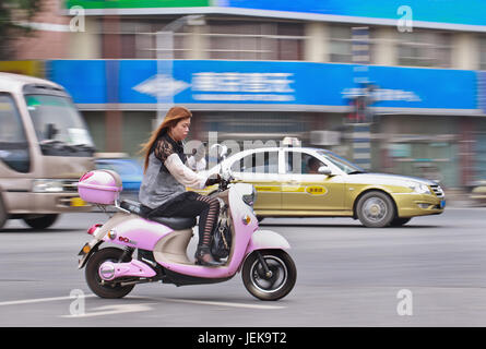 NANJING - 25. MAI 2014. Frau auf E-Bike mit Smartphone beschäftigt. China hat etwa 500 Millionen Smartphone-Nutzer, und die Zahl steigt. Stockfoto