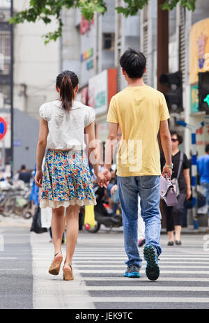 NANJING-MAI 25-2014. Jugendliches Paar geht Hand in Hand auf die Straße. Liebe, Romantik und Dating sind entmutigt, wenn Menschen jung sind. Stockfoto