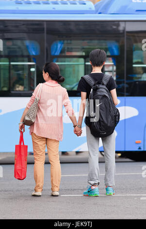 NANJING-MAI 25-2014. Mutter nimmt ihren Sohn bei der Überquerung der Straße an der Hand. Der Status der Frauen in China wird im letzten Jahrzehnt immer besser. Stockfoto