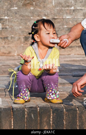 PINGYAO-CHINA-SEPT. 6, 2006. Das Kind isst Eis aus der Hand der Väter. Aufgrund der Ein-Kind-Politik Chinas (seit 1979) haben Familien nur ein Kind. Stockfoto