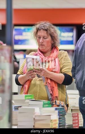 AMSTERDAM-OCT.23, 2015. Frau im Duty Free Buchladen am Flughafen Schiphol. Reisende können im Einkaufsviertel kostenlos einkaufen. Stockfoto