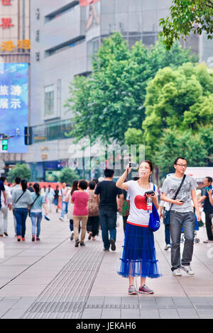 Chinesische Frau nimmt ein Foto mit einer Canon Powershot Kamera. Die PowerShot Linie hat sich als sehr erfolgreich für Canon. Stockfoto