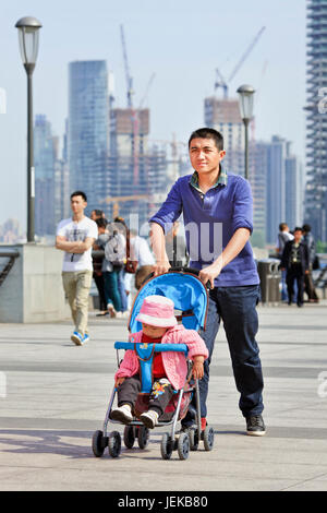 Junger Vater mit Baby Auto. Nach 30 Jahren des China Unterbringung von vielen Familien nicht ein zweites Kind nehmen aufgrund der steigenden Kosten. Stockfoto