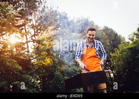 Hübscher junger Mann Vorbereitung Grill im Freien für Freunde Stockfoto