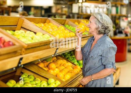 Lächelnd senior Frau riechen orange Stockfoto