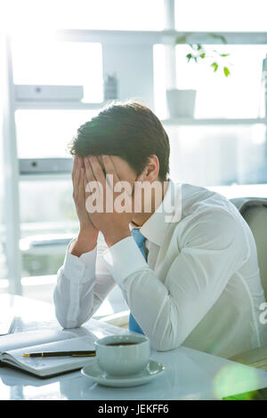 Müde asiatischen Geschäftsmann arbeitet an seinem Schreibtisch Stockfoto