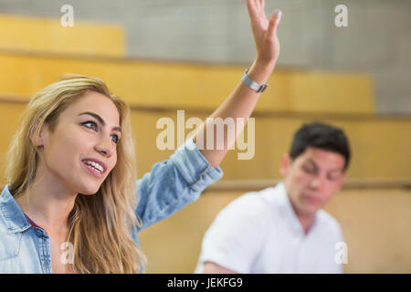 Attraktive Studentin, die Hand heben, während des Unterrichts Stockfoto