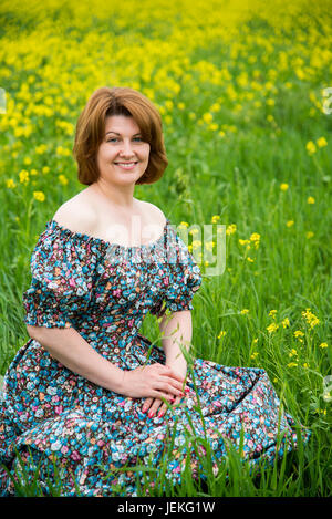 Frau im bunten Kleid sitzt auf Wiese Stockfoto