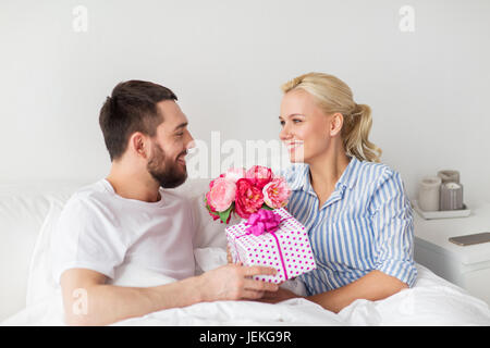 Brautpaar mit Geschenk-Box im Bett zu Hause Stockfoto