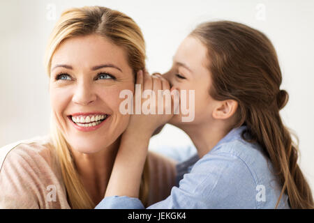 glückliches Mädchen Flüstern Geheimnis ihrer Mutter Stockfoto