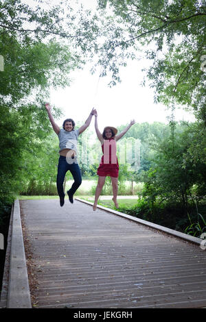 Ein junges Paar springen vor Freude auf einer Brücke, Chauray, Frankreich Stockfoto