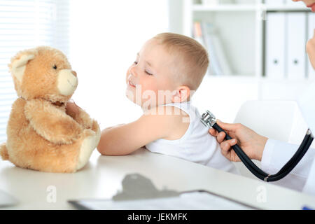 Glücklicher kleine junge Spaß beim ist von Arzt mit Stethoskop untersuchen wird. Hilfe, Pflege und Versicherung Gesundheitskonzept. Stockfoto