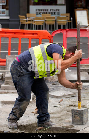 Ein Arbeiter aus dem hoch-und Tiefbau-Unternehmen "Land & Haustechnik" Betonpflaster verlegen Platten entlang der Nethergate in Dundee, Großbritannien Stockfoto