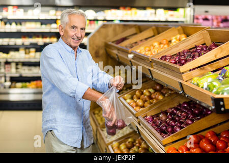 Lächelnd älterer Mann Kaufen rote Zwiebeln Stockfoto