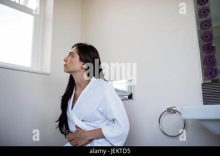 Frau im Bademantel mit Bauchweh Stockfoto