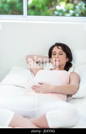 Schwangere Frau ruht auf ihrem Bett Stockfoto