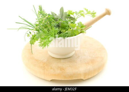 Eine Auswahl von Kräutern in einem Creme Mörser mit Stößel, stehend auf hellem Holz Schneidebrett die Verschleißerscheinungen zeigt.  Isoliert gegen weiße backg Stockfoto