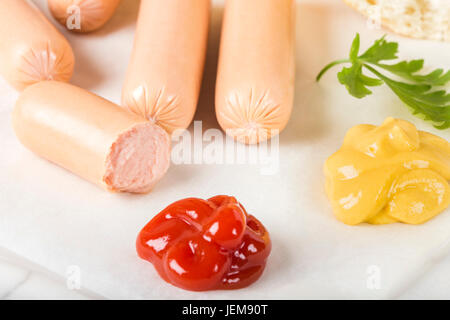 Würstchen (Frankfurter) auf Papier mit Brot, Senf und ketchup Stockfoto