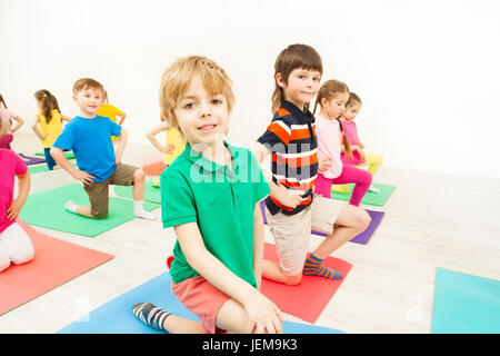 Glückliche Kinder üben Gymnastik auf Matten in der Turnhalle Stockfoto