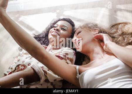 Zwei Attractine junge Frauen, auf dem Boden liegend und Selfie zu machen. Stockfoto