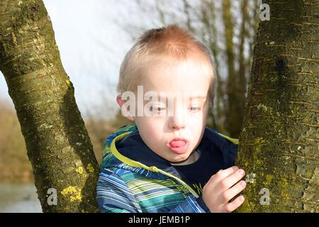 Nachdenkliche junge mit Syndrom nach unten, die Bäume umarmt. Stockfoto