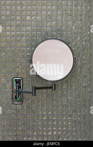 Modernes Design Kreis förmige Falten Bad Spiegel gegen eine Wand mit grauen Keramikfliesen. Stockfoto