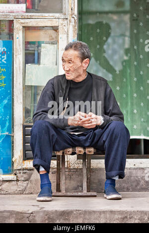 Peking - SEPT. 28. Alte chinesische Mann sitzt vor seinem Wohnhaus, in einem Hutong Gegend im alten Zentrum von Peking. Stockfoto