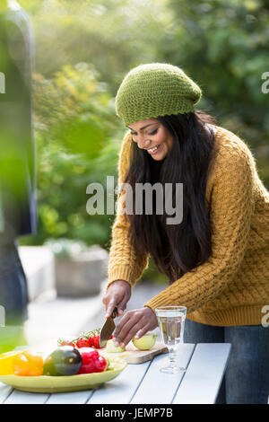 Lächelnde junge Frau Schneiden von Gemüse Stockfoto